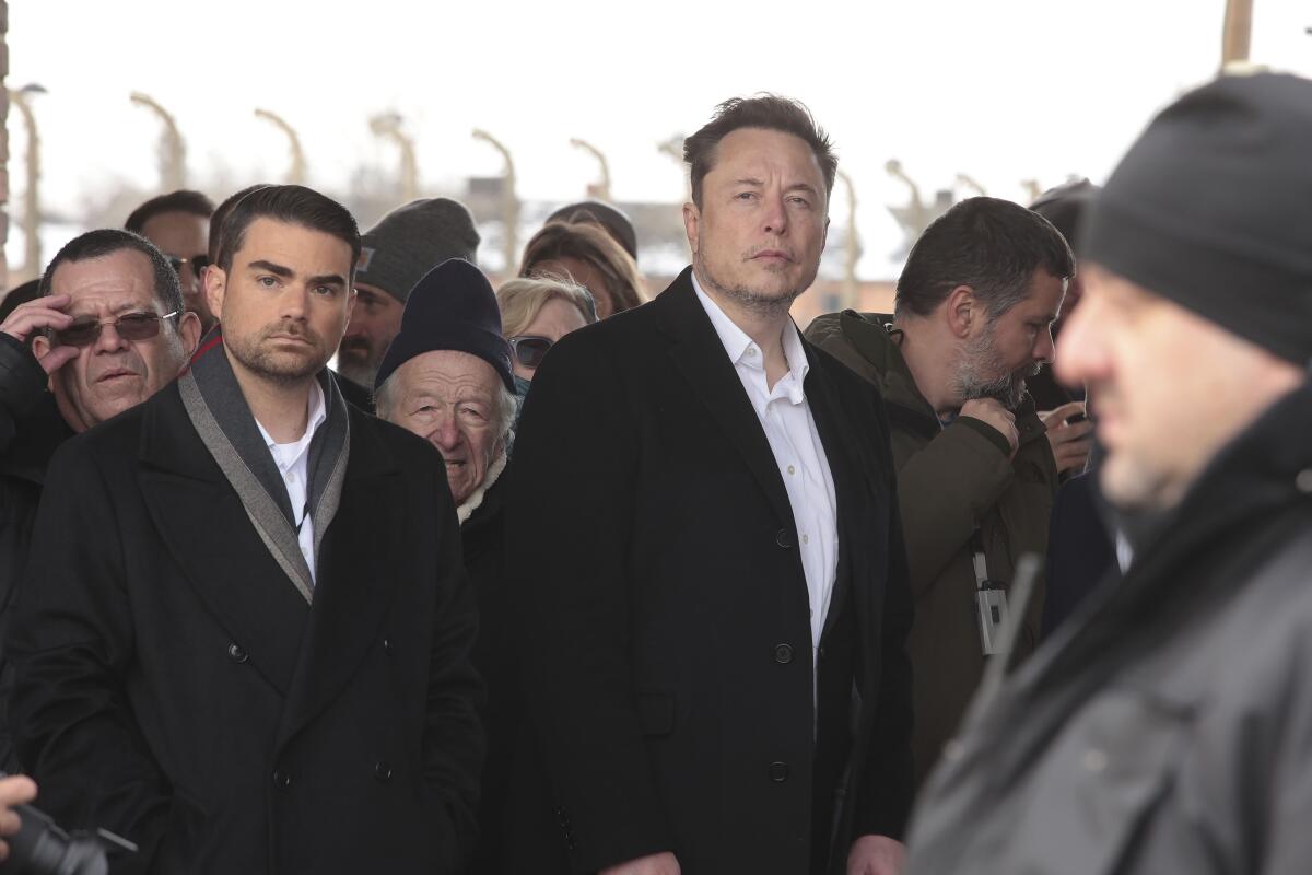 Elon Musk, al centro, en el sitio del antiguo campo de concentración Auschwitz-Birkenau en Polonia