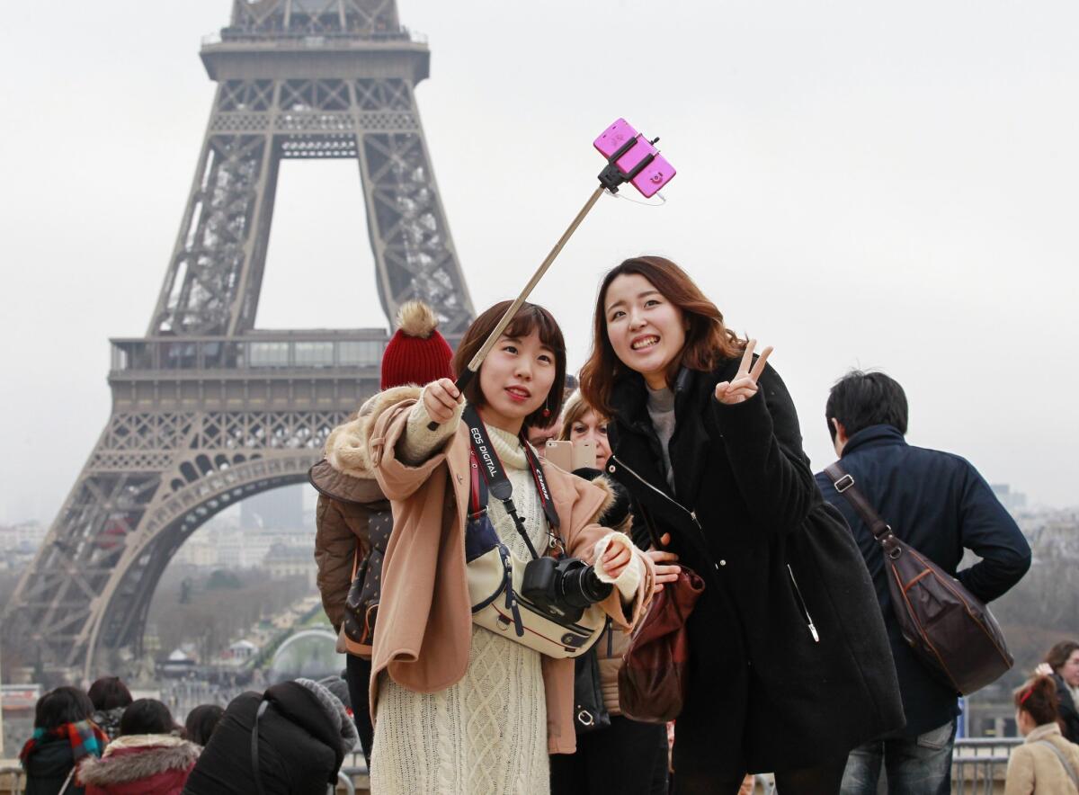 Tourists use a selfie stick at the Eiffel Tower in January. The Louvre in Paris hasn't yet banned them though other museums have.