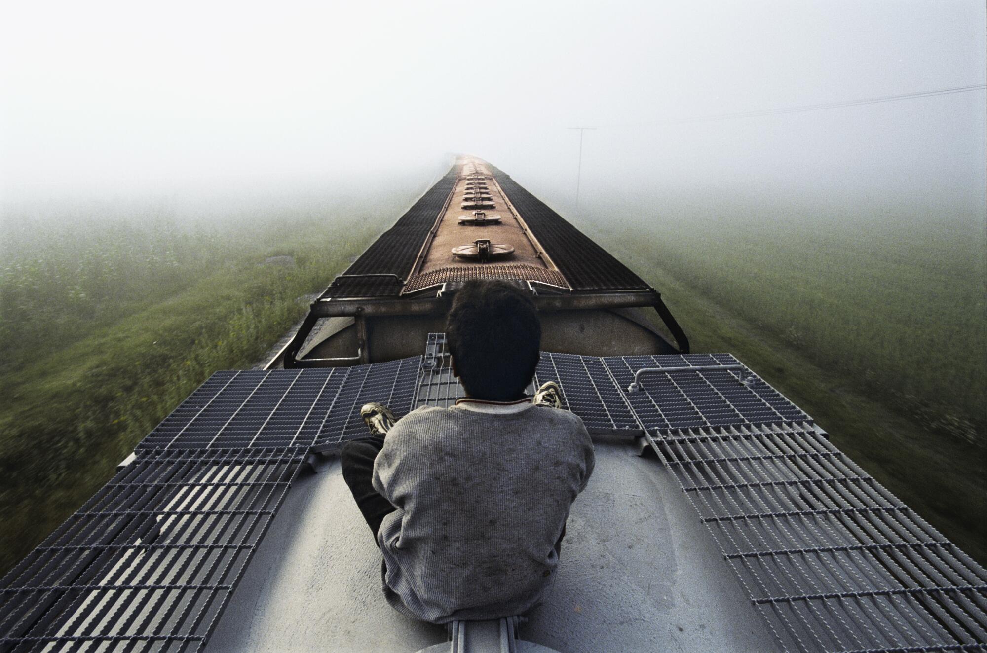 A Honduran boy rides atop a freight train