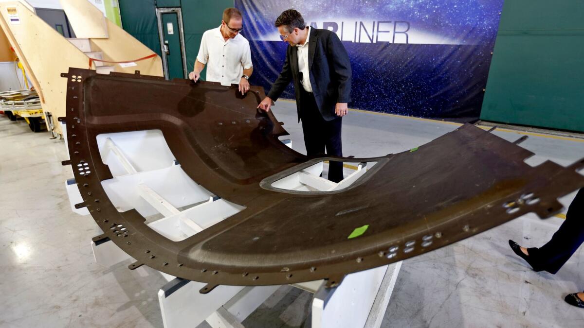 Rob Adkisson, right, chief engineer with Boeing's Commercial Group Program, examines a capsule heat shield component with David Schiller, aerostructures lead for the company's commercial crew program. (Al Seib / Los Angeles Times)