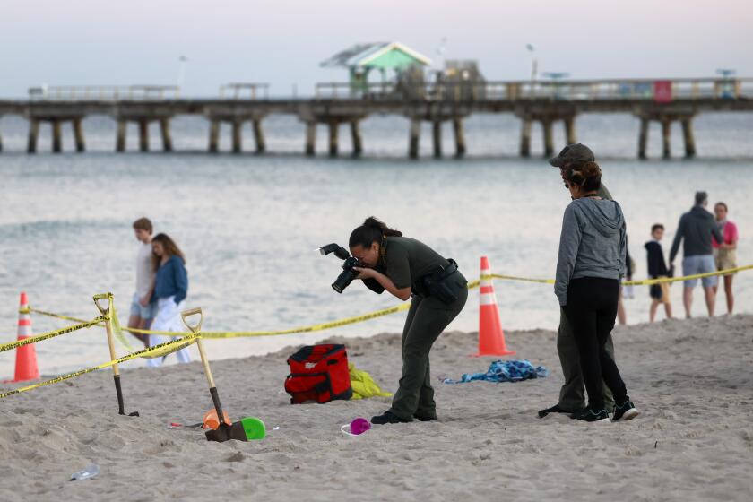 Investigators on the beach in Lauderdale-by-the-Sea, Fla., take photos of the scene of a sand collapse on Tuesday, Feb. 20, 2024. A young girl was buried in sand and died Tuesday when a deep hole she was digging with a little boy collapsed on them both at a south Florida beach, authorities said. (Mike Stocker/South Florida Sun-Sentinel via AP)