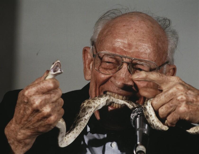 Rios' collection includes this photo and description: An elderly man biting a live snake in front of a microphone.