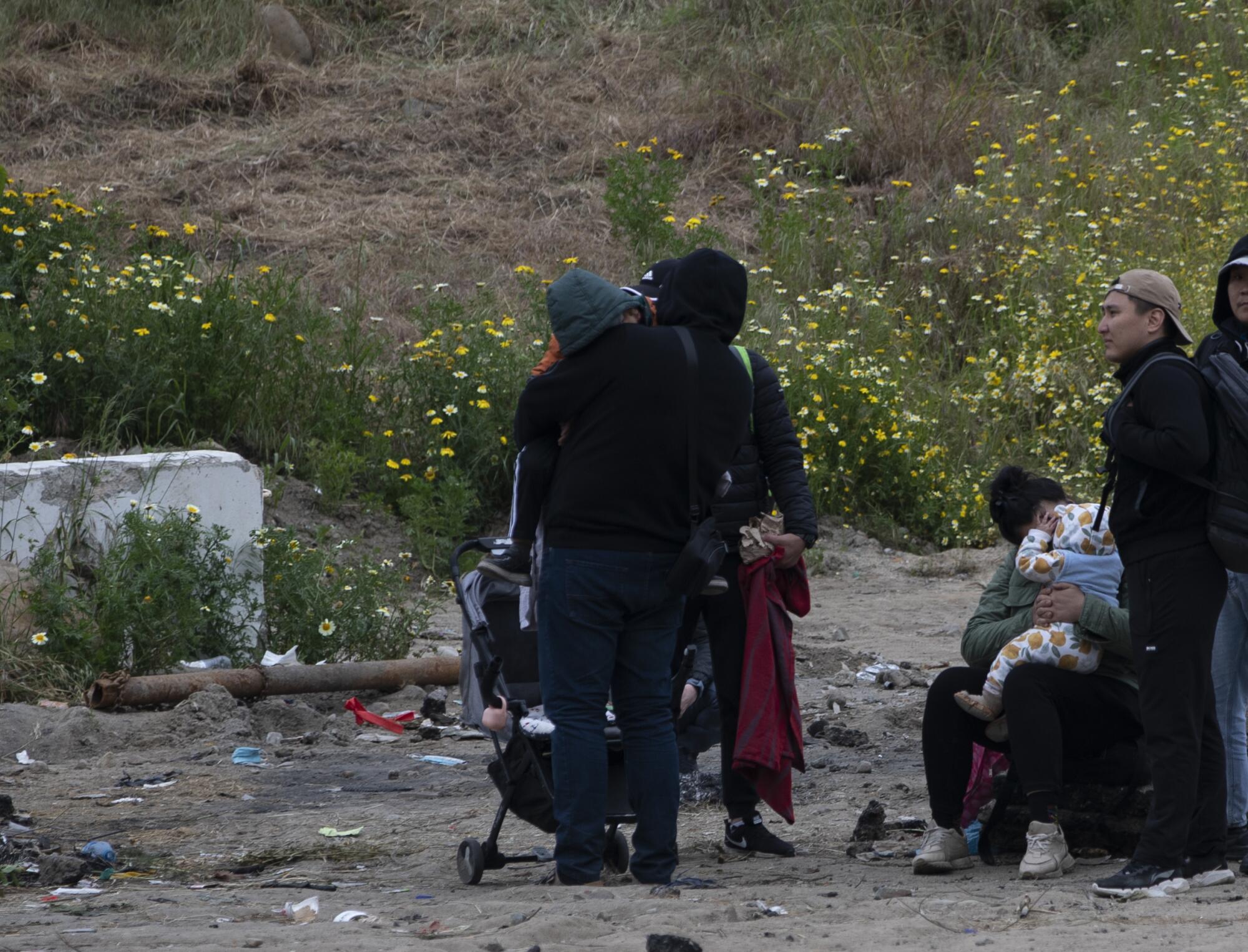 A woman with a baby sits between the border walls