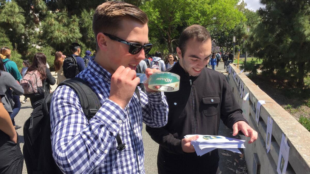 Peter Van Voorhis, left, posts campaign flyers on UCI campus with help from friends George Novshadyan.