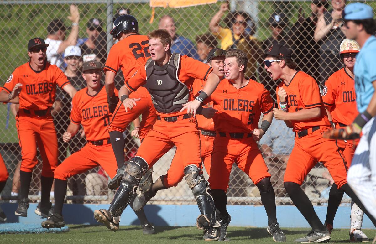 Trent Grindlinger of Huntington Beach, in catcher's vest, cheers after teammate Nate Cox (22) crosses home plate Tuesday.
