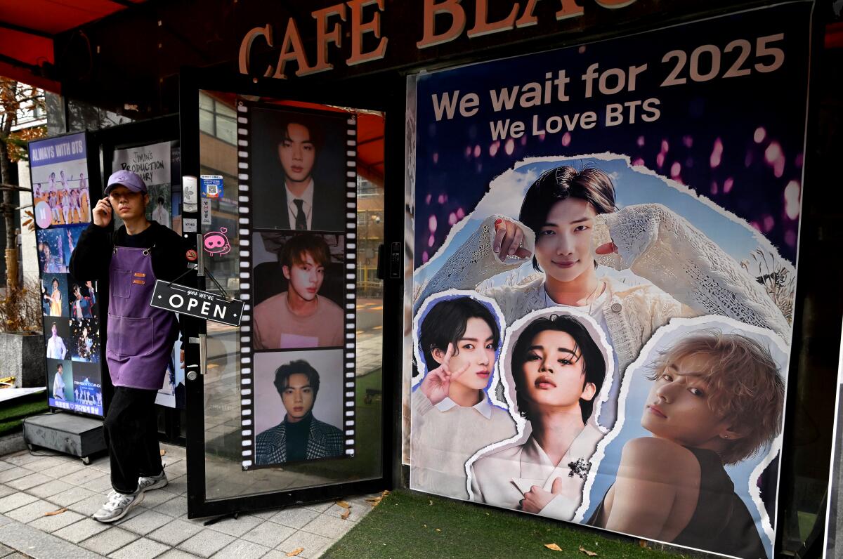 A man walks past a poster of South Korean K-pop group BTS.