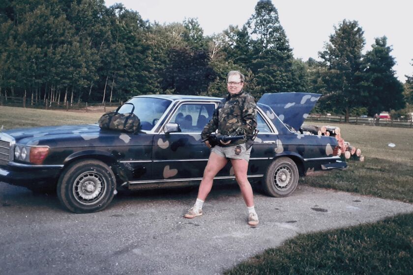 A man brandishing a rifle in front of camouflage-painted Mercedes-Benz in the documentary "2nd Chance."
