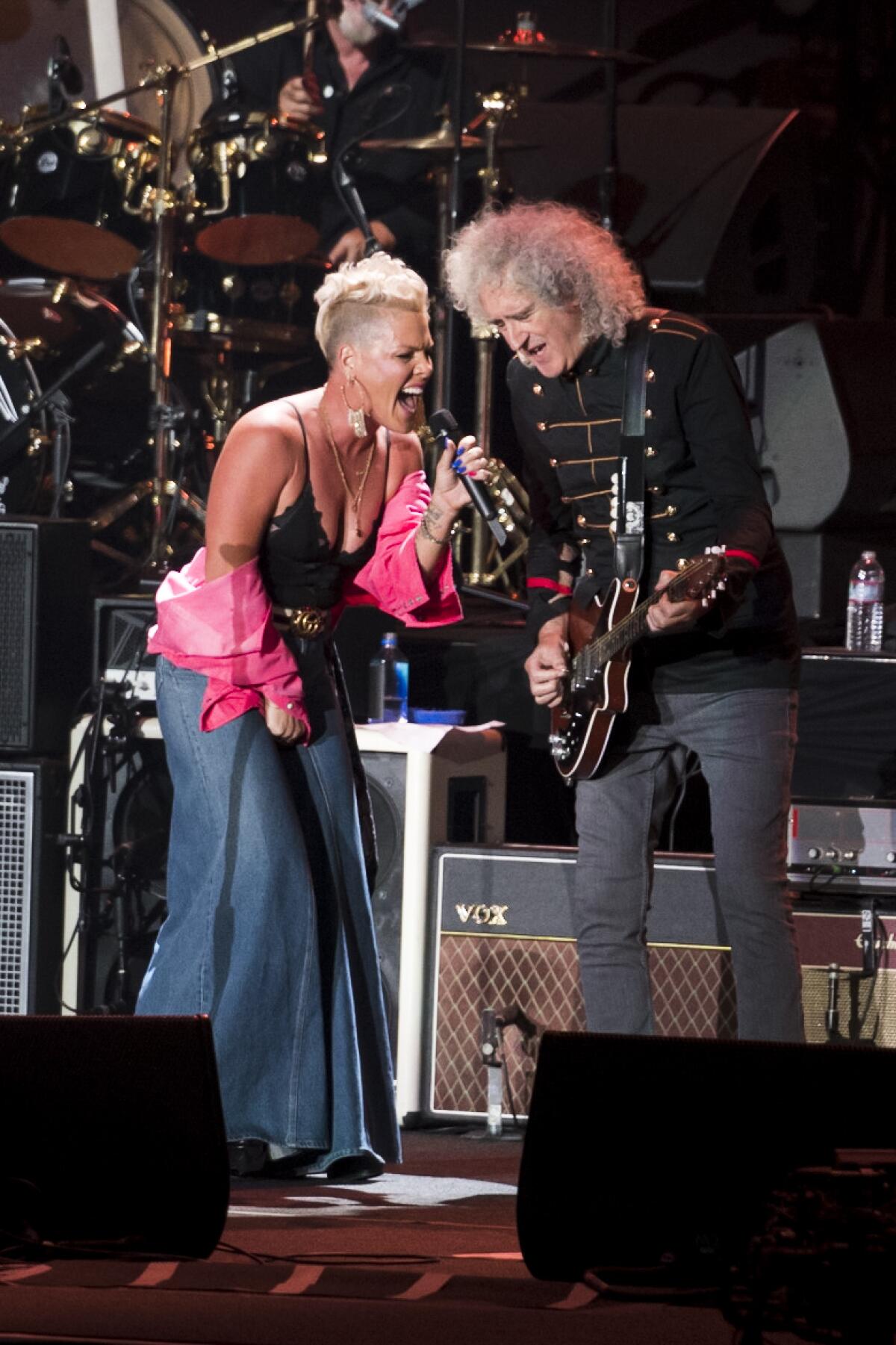 A female singer and a rock guitarist perform together onstage.