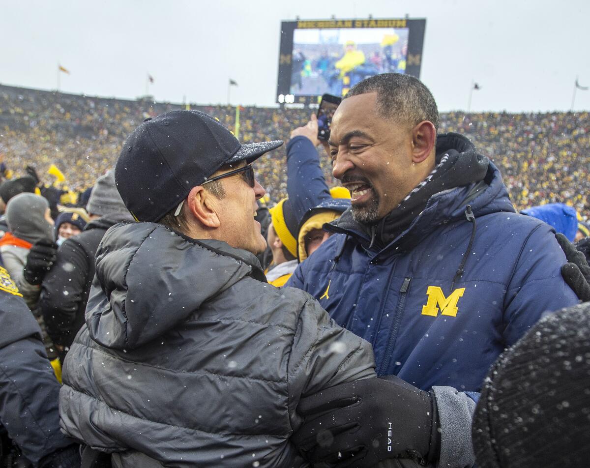 Michigan football coach Jim Harbaugh, left, is congratulated by Wolverines basketball coach Juwan Howard on Nov. 27, 2021. 