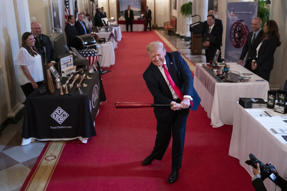 President Trump swings a baseball bat inside the White House on Thursday during an event celebrating American businesses.