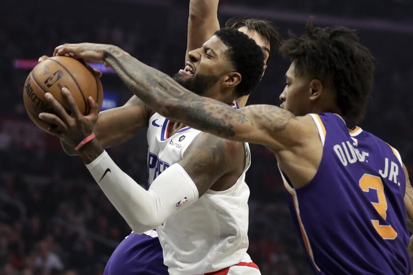 Phoenix Suns forward Kelly Oubre Jr., right, blocks a shot by Los Angeles Clippers forward Paul George during the first half of an NBA basketball game in Los Angeles, Tuesday, Dec. 17, 2019. (AP Photo/Chris Carlson)