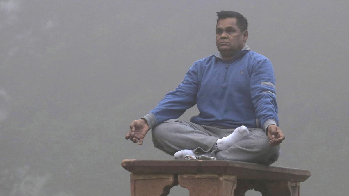 A man meditates as the Lodhi garden is engulfed in heavy smog in New Delhi.