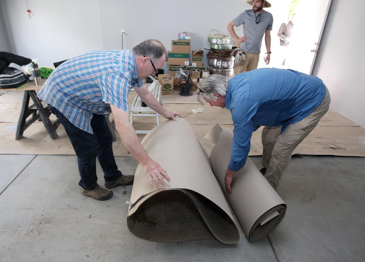 Volunteer Scott Carpenter, of La Cañada, and Habitat for Humanity fundraiser Otis Marston, roll up thick paper that protected a garage floor at one of Habitat for Humanity's Chestnut Street homes on Friday, March 11, 2016. The project broke ground in July 2014.