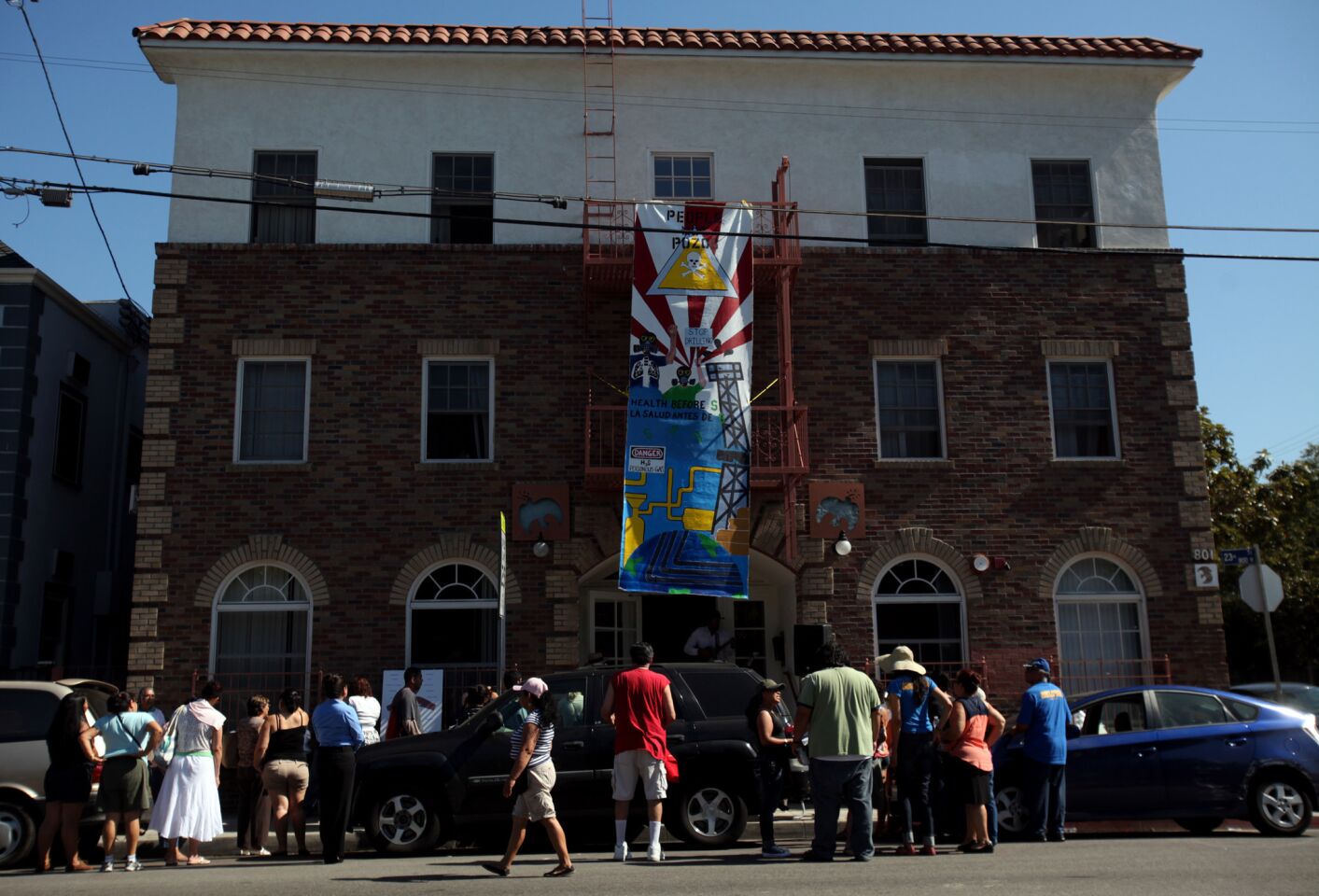 About 40 members of the community gather in front of Monic Uriarte's building in the University Park neighborhood. In what they called an "action," they hung a banner that read "People Not Pozos" ("People Not Wells") and spoke about the air quality in their community.