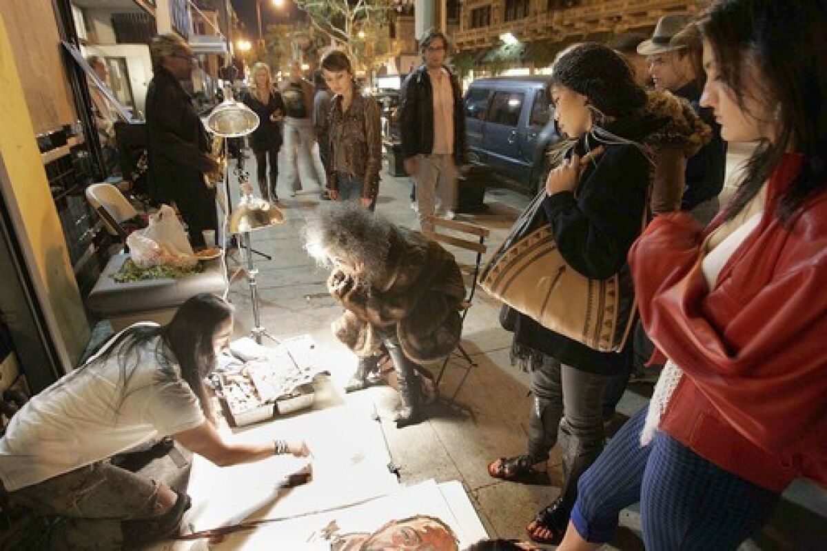 CARNIVAL ATMOSPHERE: A street artist painting a portrait draws a small crowd in downtown. The monthly art walk draws 2,000 to 3,000 visitors to more than 40 galleries.
