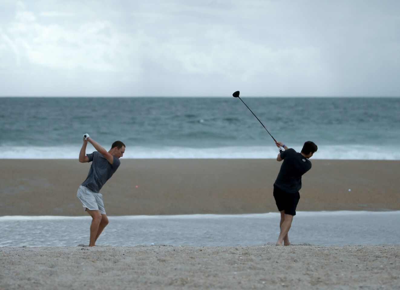 Jacob Whitehead, left, and Matt Jones hit golf balls into the surf as Hurricane Florence approaches in Wrightsville Beach, N.C.