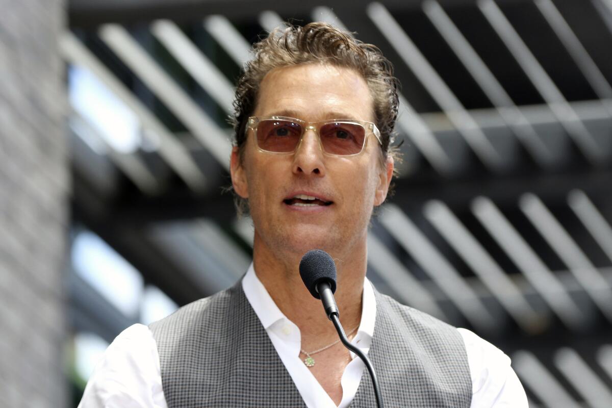 Matthew McConaughey wearing sunglasses and speaking into a microphone