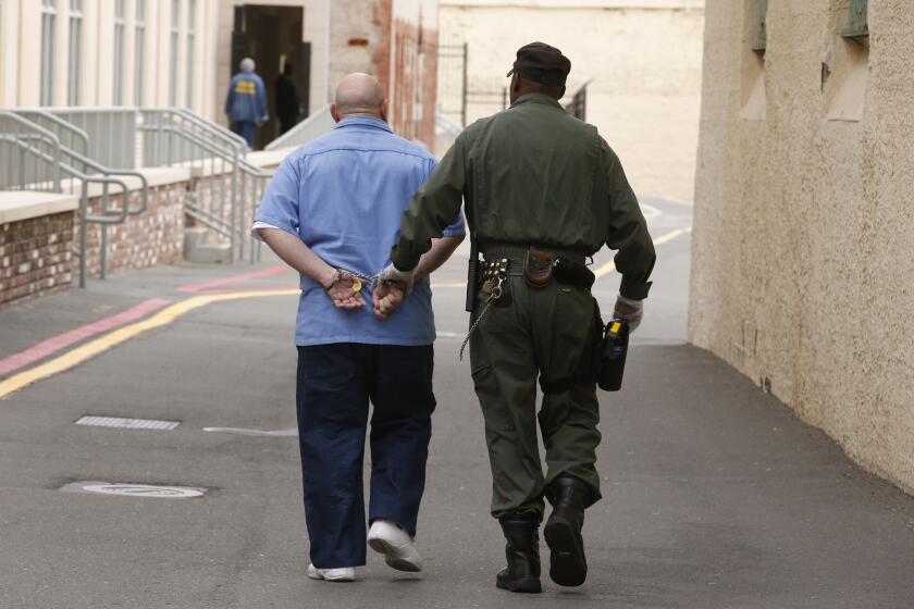 A death row inmate is escorted across the yard away from the East Block at San Quentin while on his way to a morning appointment.