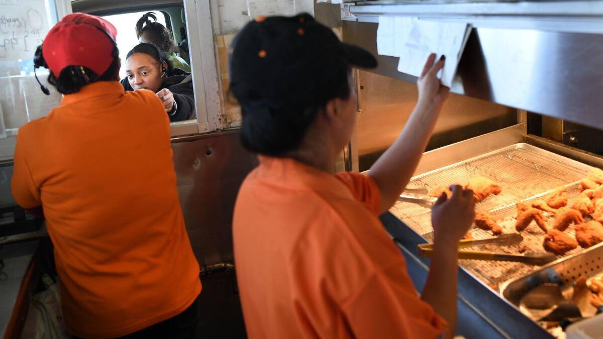 Customers receive their food through a bulletproof window at a Louisiana Famous Fried Chicken in South L.A.