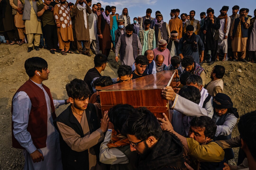 Caskets are carried toward a gravesite.