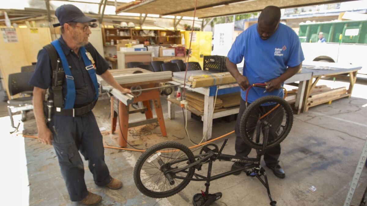 Dafferine Frost, right, is the first person at Father Joe's Villages to complete a new bicycle mechanic program taught by Joe Ryan, left, Father Joe's Village maintenance supervisor.