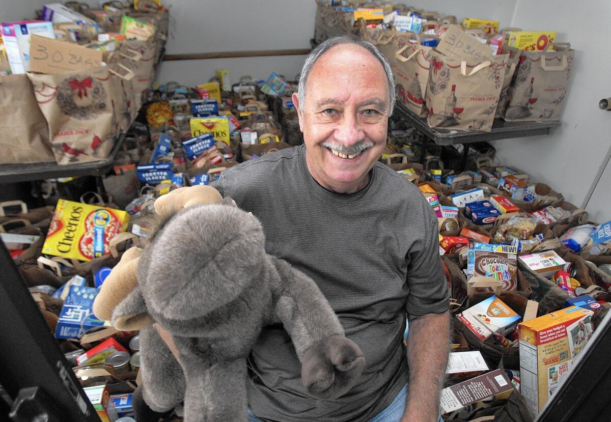 Bill Latuf of La Crescenta is a 12-year volunteer with the Los Angeles Sheriff's Department's Crescenta Valley station, pictured with nearly 200 bags of groceries in a Bob Smith Toyota storage area in La Crescenta. Food and toys will be distributed to families in need this Saturday at Crescenta Valley Park.