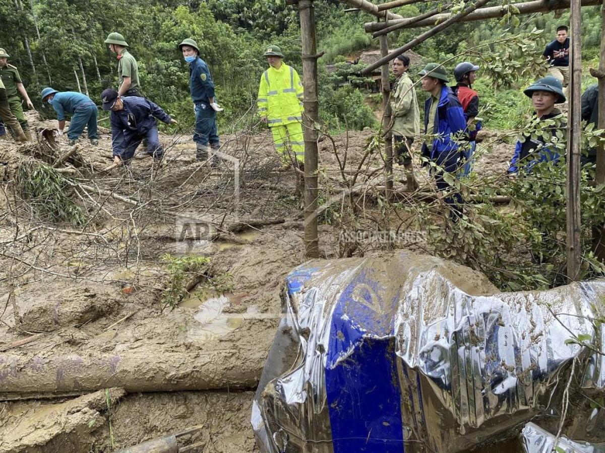 Rescue workers clear mud and debris brought down by a flood in Lang Nu hamlet in Lao Cai province, Vietnam.