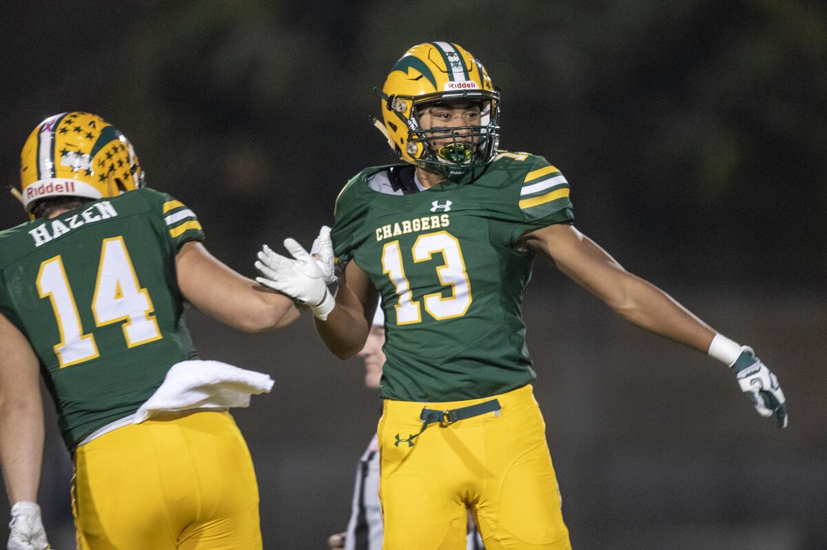 Edison's Christian Hazen, left, high-fives Cole Koffler after he scored a touchdown against Heritage in the first round of the CIF Southern Section Division 3 playoffs on Friday at Huntington Beach High.