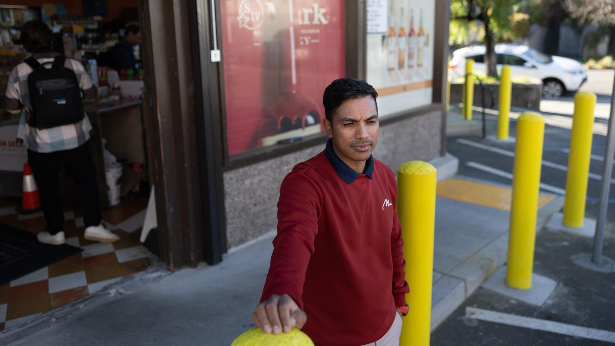 David Shrestha, co owner of Eddie's Drive In Liquors, stands with concrete-filled pipes.