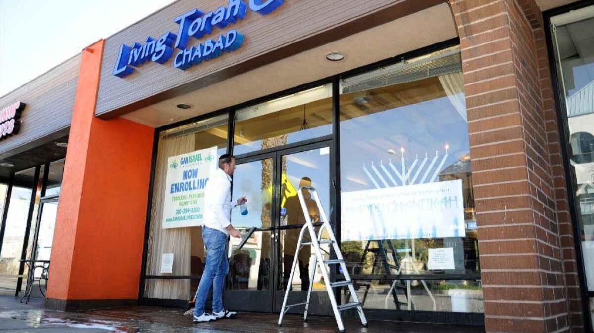 Jacob Silver finishes washing the windows outside The Living TorahCenter after the building was vandalized with feces.