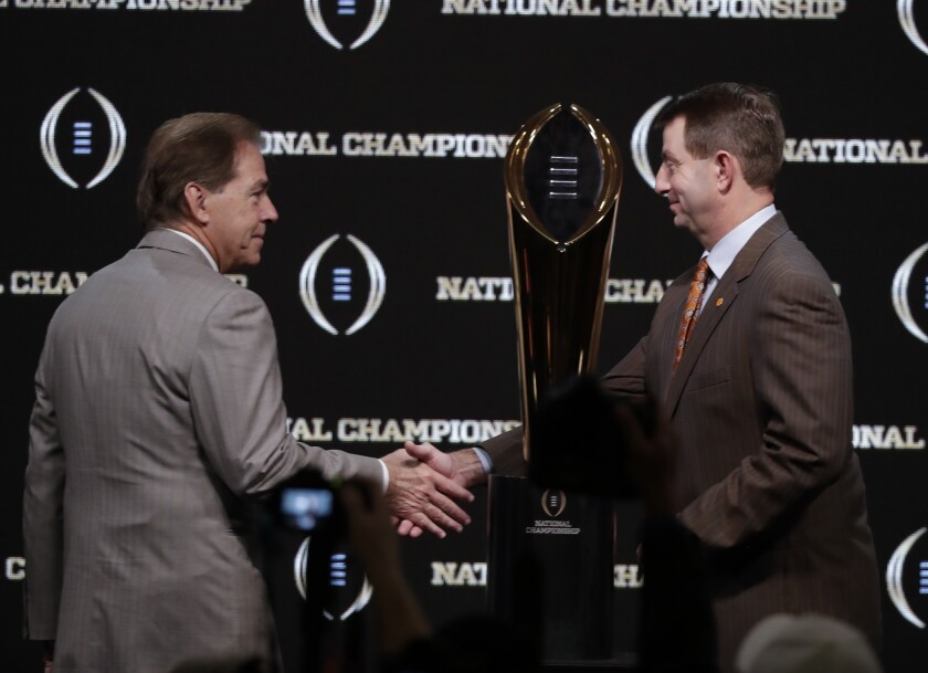 Alabama head coach Nick Saban and Clemson head coach Dabo Swinney pose with the trophy at a news conference for the College Football Playoff championship game on Jan. 6 in Santa Clara.