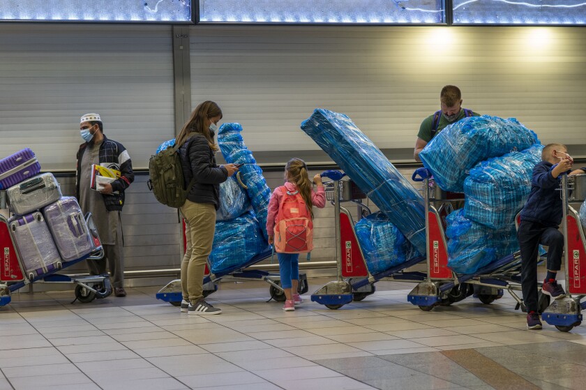 People line up with luggage at an airport.