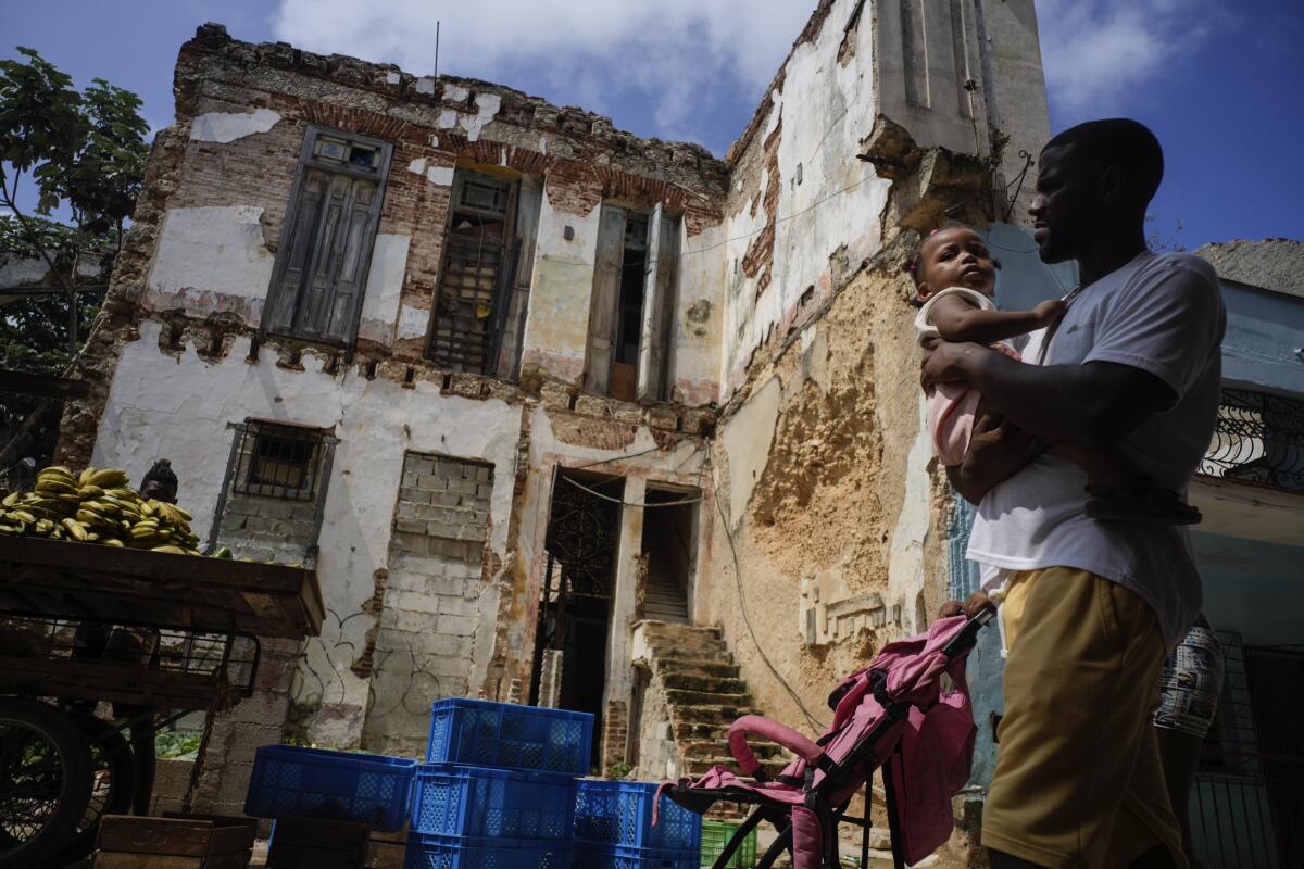 Residents walk past dilapidated mansion on Villegas Street in Havana, Cuba.
