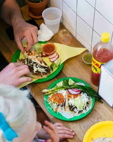 Plates of Mexican food on a wooden counter next to a white tiled wall