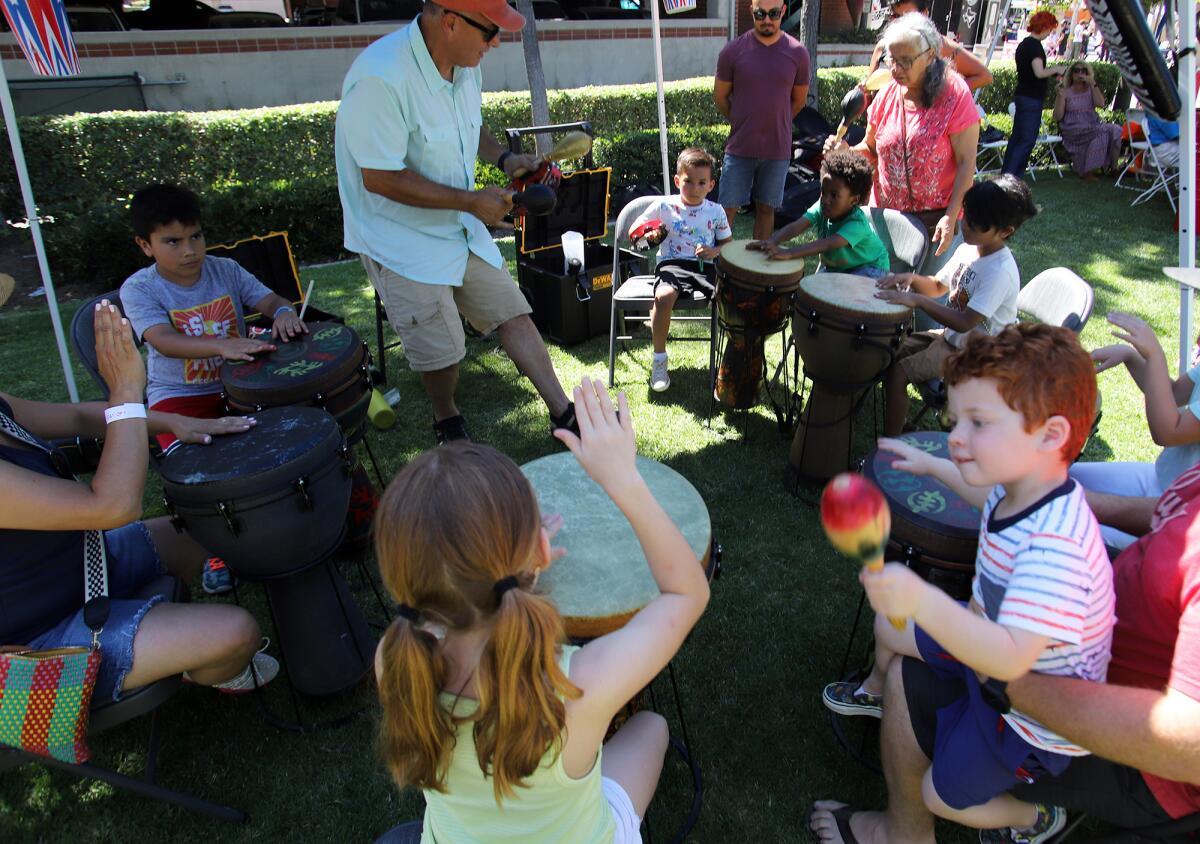 Kids learn to play the congas and the maracas in the Kids Korner at Day of Music Fullerton. 