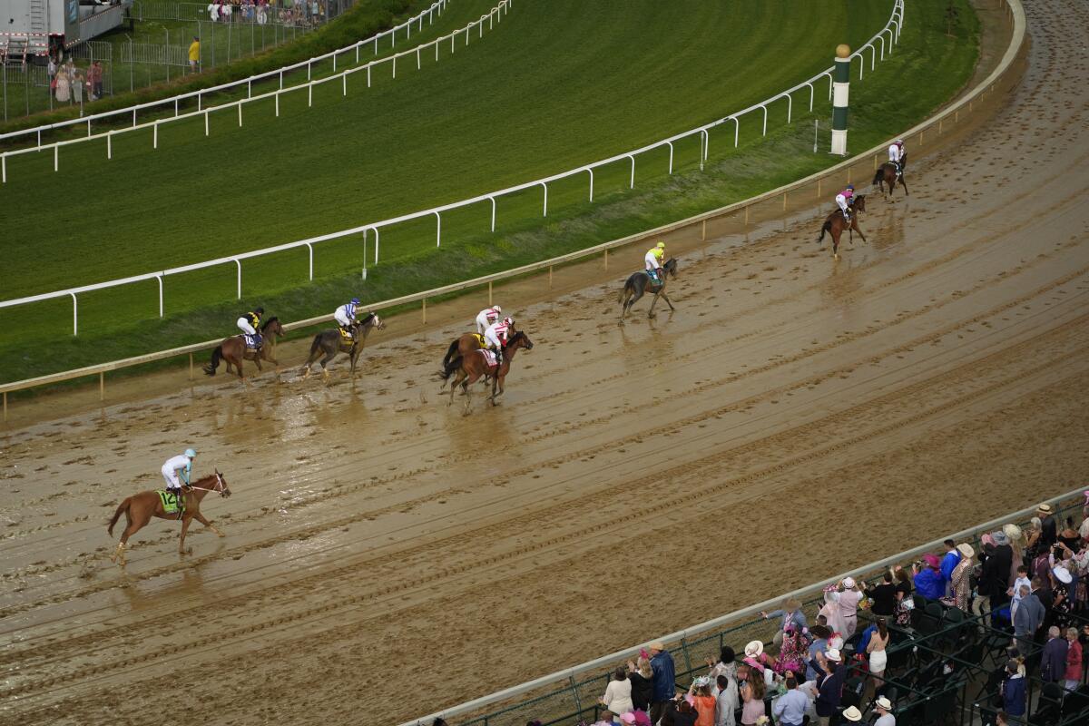Horses run on a wet track during the Kentucky Oaks race Friday in Louisville, Ky.
