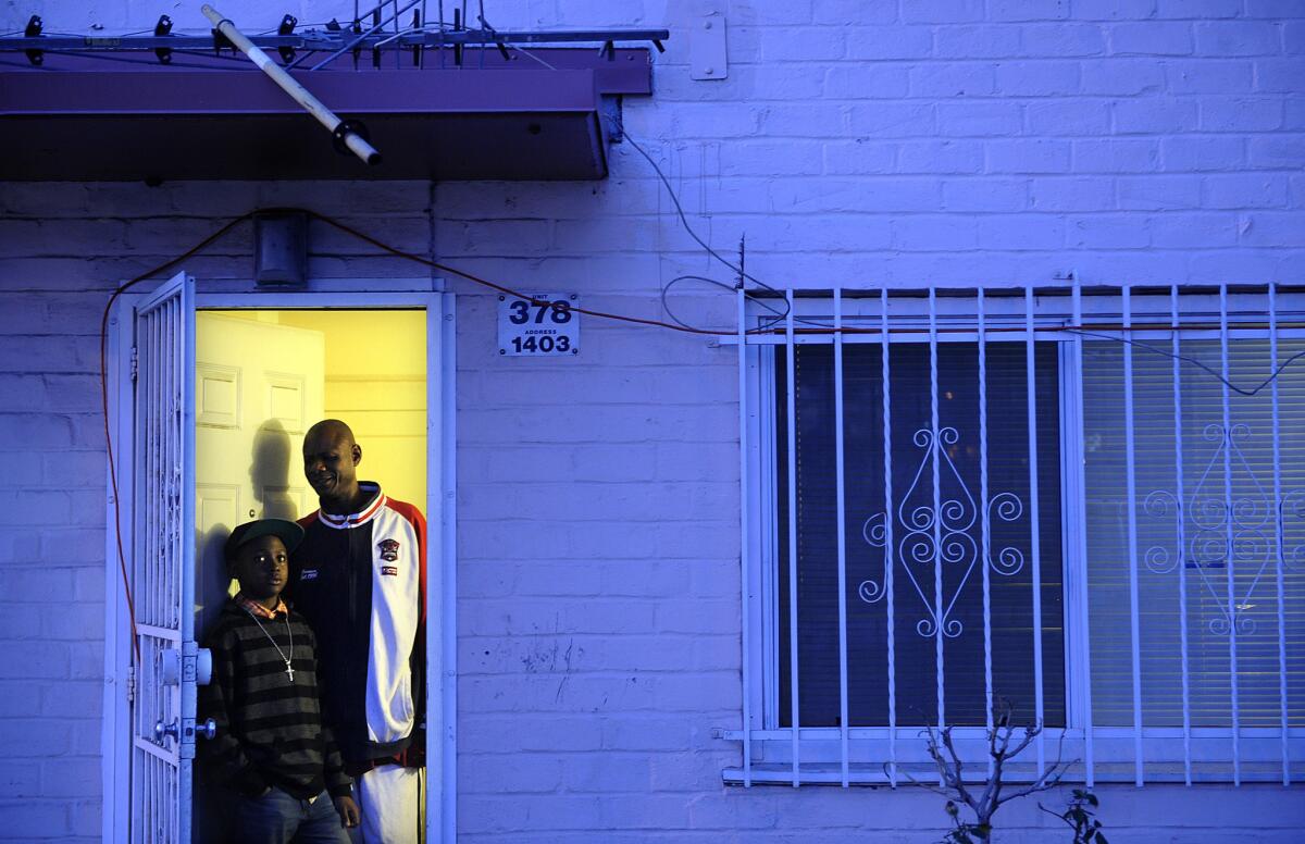 Jeff Littrel and his son Malik stand in the doorway of their home in the Ramona Gardens housing project in Los Angeles. The Littrel's were were eating dinner when a rock thrown by young men crashed through their living room window and to this day have kept the rock as a reminder and inspiration.