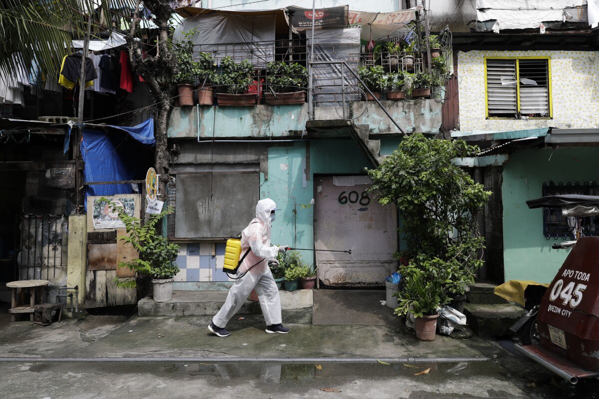 A man wearing a protective suit disinfects an area placed under stricter lockdown measures to curb the spread of COVID-19 in Caloocan city, Philippines on Friday, Aug. 14, 2020. The capital and outlying provinces is still under lockdown due to rising COVID-19 cases. (AP Photo/Aaron Favila)