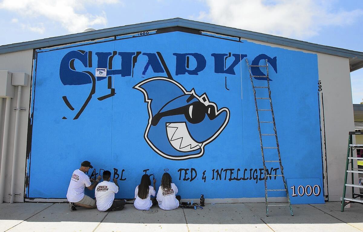 Michael Howard, founder of Operation Clean Slate, a mural-making organization, paints a mural with Rea Elementary school students Ricardo Contreras, 11, Xamantha Rocha, 11 and Alicia Airey, 10 on a wall at school on Tuesday.