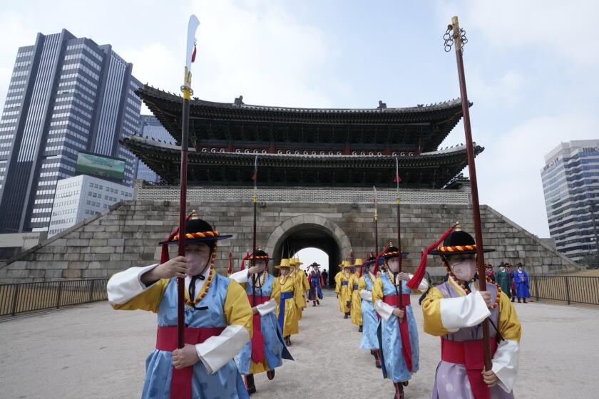 Performers wearing traditional guard uniforms and face masks march during a reenactment of opening and closing of the gate at the Sungnyemun Gate in Seoul, South Korea, Tuesday, March 15, 2022. South Korea had its deadliest day yet of the pandemic on Tuesday as the country grapples with a record surge in coronavirus infections driven by the fast-moving omicron variant. (AP Photo/Ahn Young-joon)