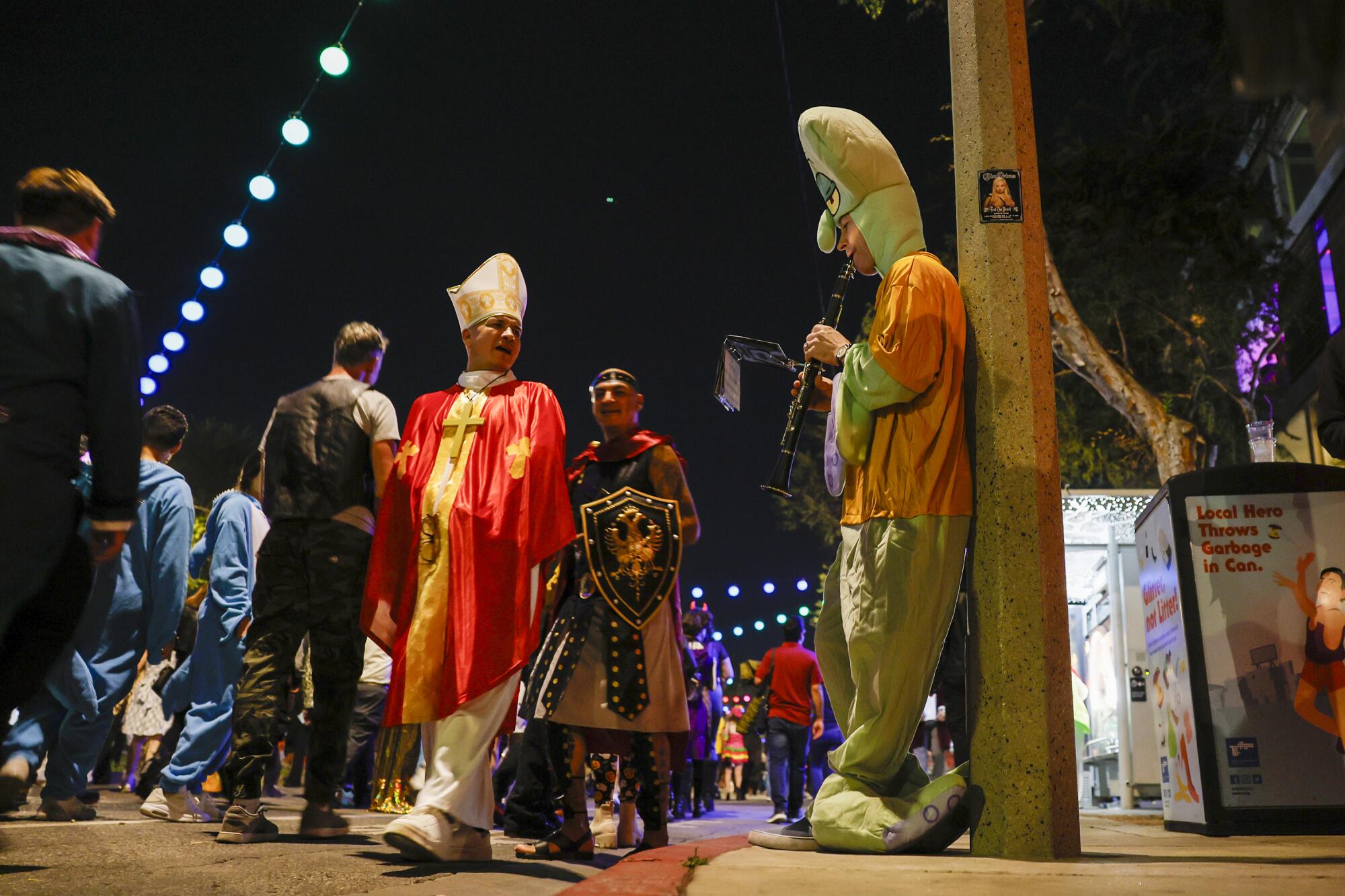 Justin Marchert as "Squidward," plays a clarinet as Halloween revelers pass by.  