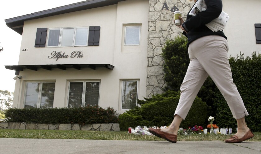 A passerby walks past a makeshift memorial at the Alpha Phi sorority house, near which two women were killed during Friday night's mass shooting in the Isla Vista area near UC Santa Barbara.