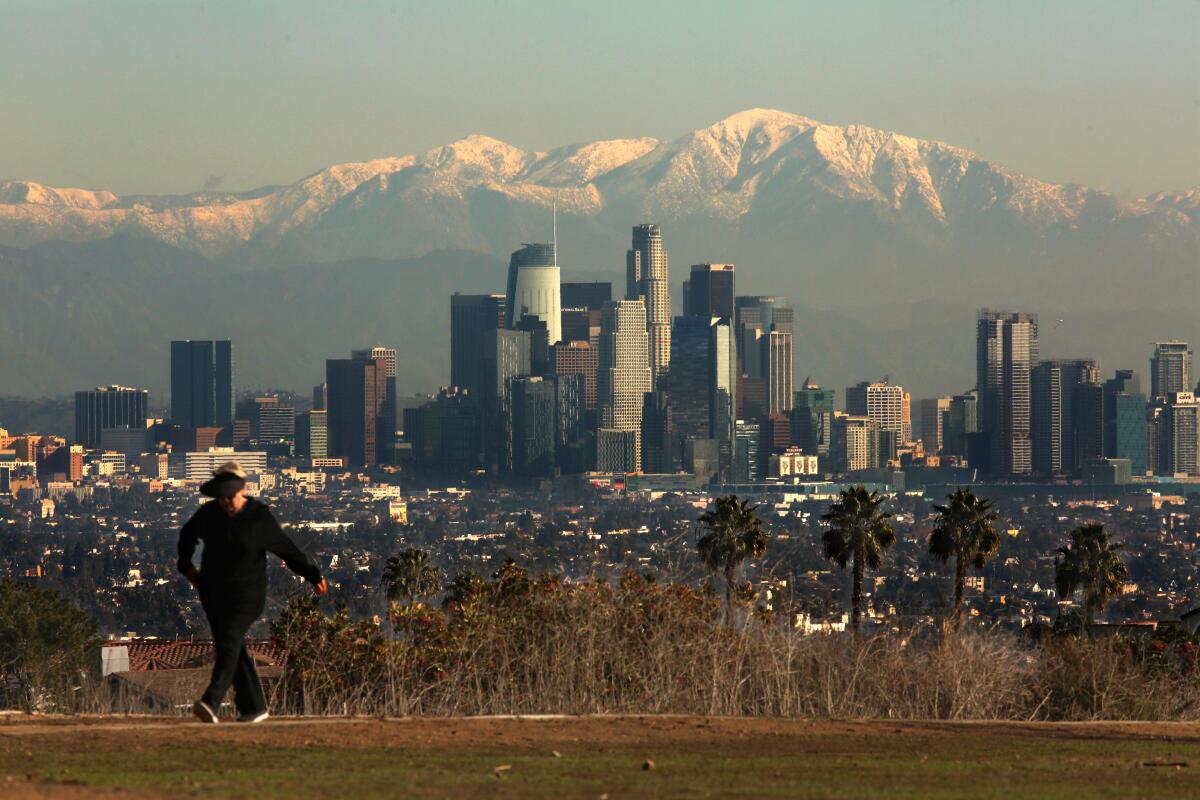 The downtown Los Angeles skyline with snow-covered mountains in the backdrop.