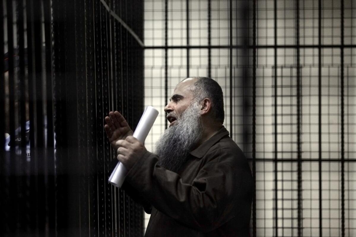 Abu Qatada speaks to reporters from a courtroom cage prior to a Sept. 7 hearing in his case in Amman, Jordan.