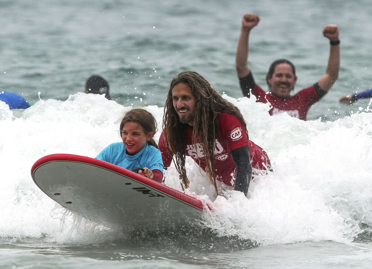 Professional surfer Rob Machado surfs with Cami Wood, 8, who lost her left leg due to a rare tissue infection, during the Challenged Athlete Foundation Youth Expression Session at the Switchfoot Bro-Am music and surf festival.