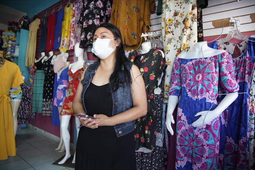 Silvia Lorena Abrego Hernandez, 33 wearing a mask, standing in her sisters clothing store recalls the moment she took her husband to Clinica 20. She holds her phone while speaking on May 28, 2020 in Tijuana, Baja California. Jose Luis Hebrero Cisneros, 35 died on April 12 after entering the hospital on April 6. He first started getting a fever in the ultimate days of March but they wouldn't let him off work.