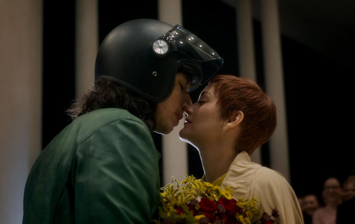 A man in a motorcycle helmet and a woman with short hair embrace