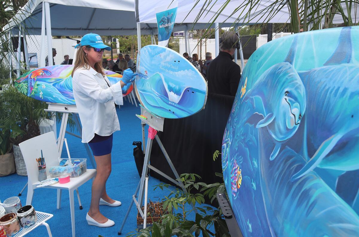 Melissa Murphy paints on surfboards during the City of Hope Seacliff ribbon-cutting ceremony.