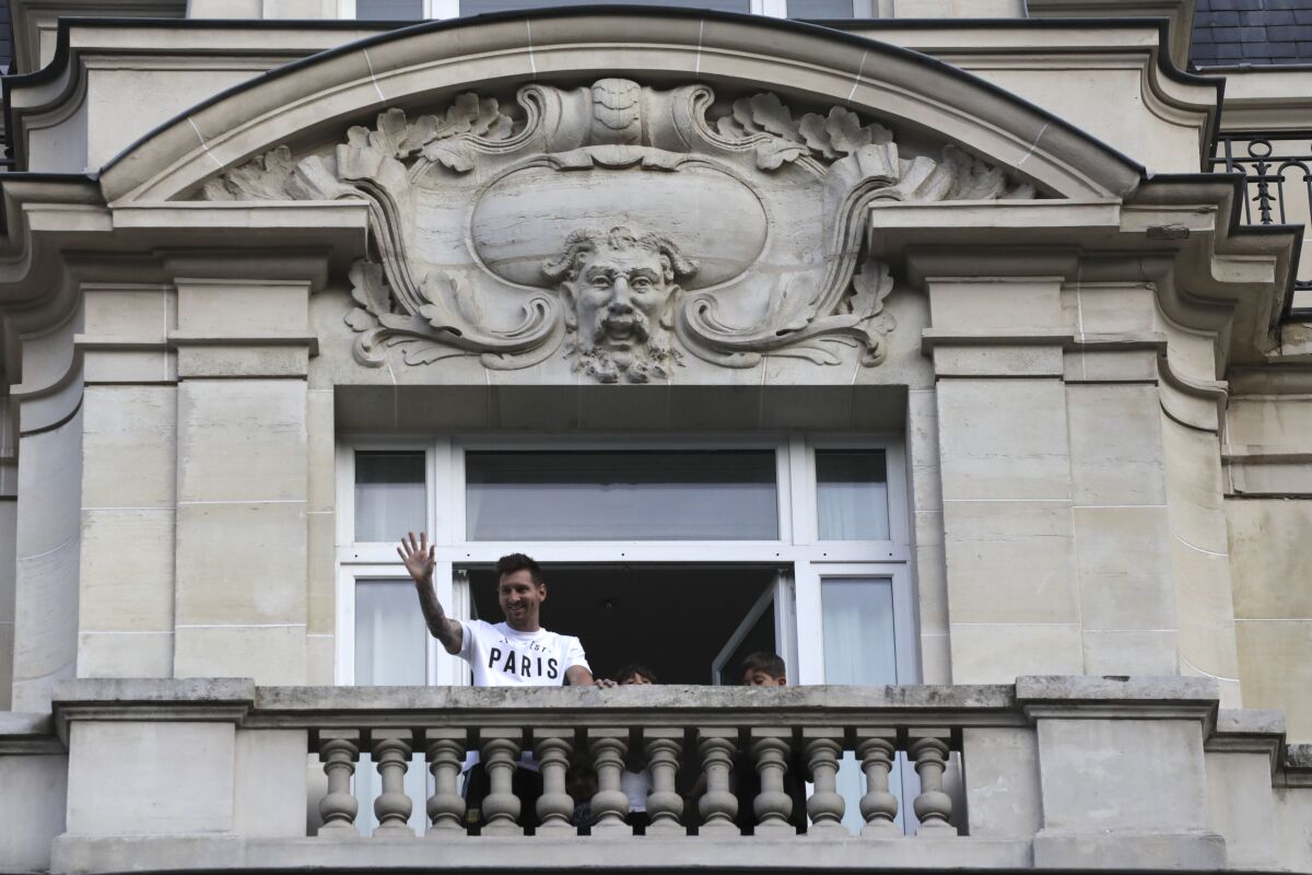 Argentinian soccer star Lionel Messi waves to supporters from his hotel balcony in Paris, Tuesday, Aug. 10, 2021. Lionel Messi finalized agreement on his Paris Saint-Germain contract and arrived in the French capital on Tuesday to complete the move that confirms the end of a career-long association with Barcelona. (AP Photo/Adrienne Surprenant)