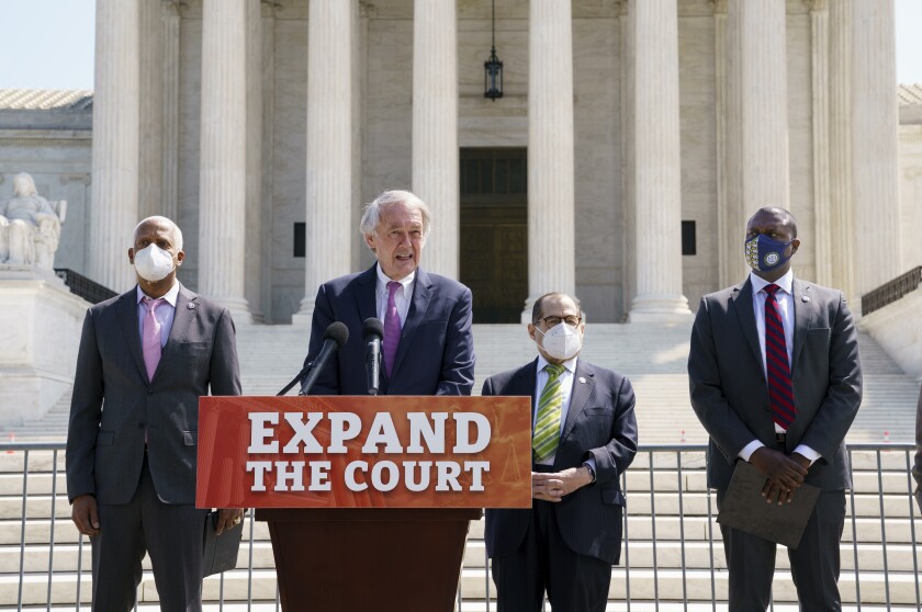 Four Congressmen hold a small banner that says "Expand the court" outside the Supreme Court building.